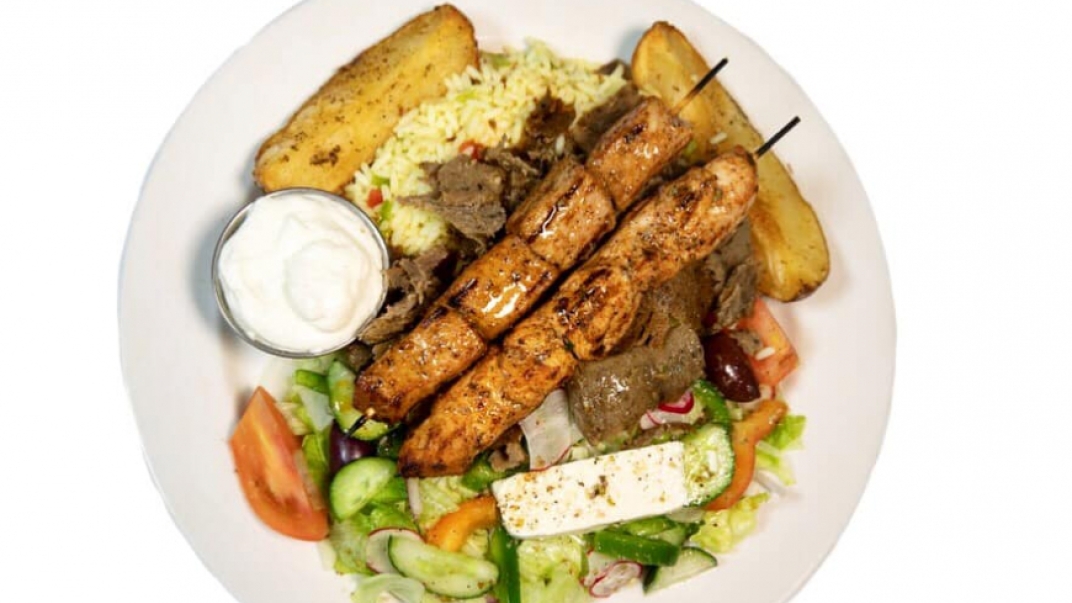 A souvlaki plate with kebabs, a salad, and rice. 