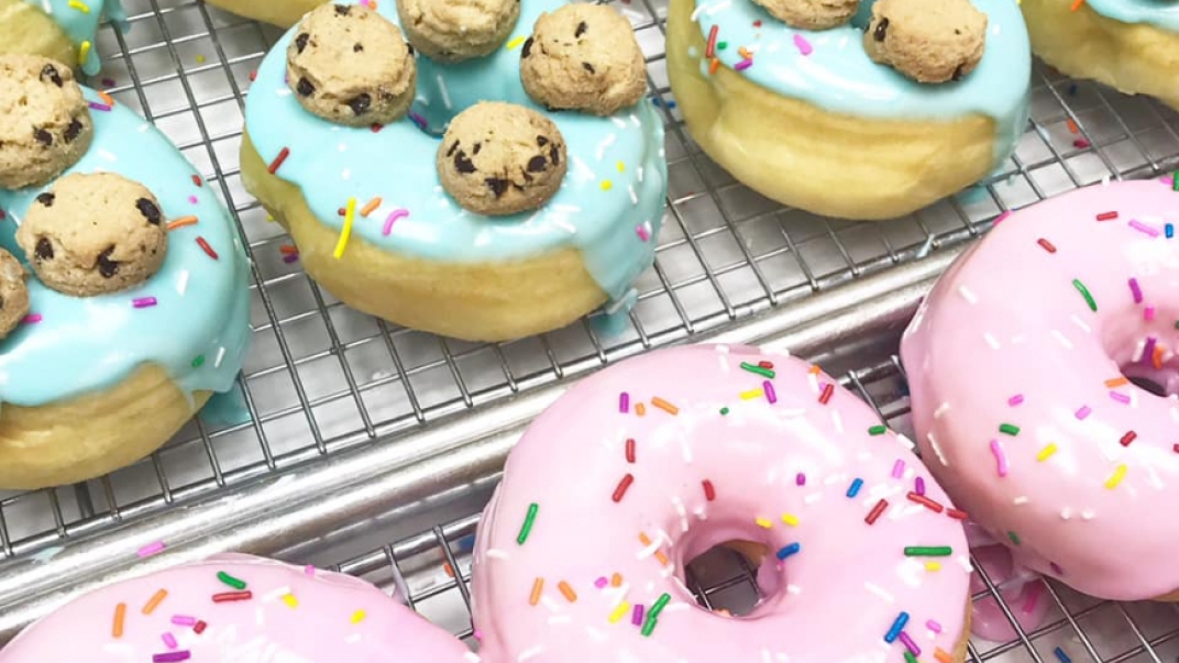 donuts with pink icing and sprinkles and blue icing topped with cookies