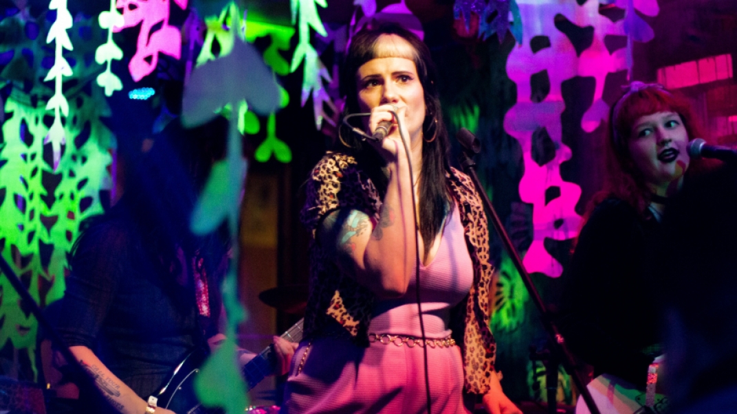 Woman singing with neon colours shining in the background