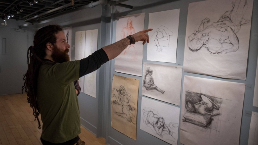 person pointing at sketches on a gallery wall
