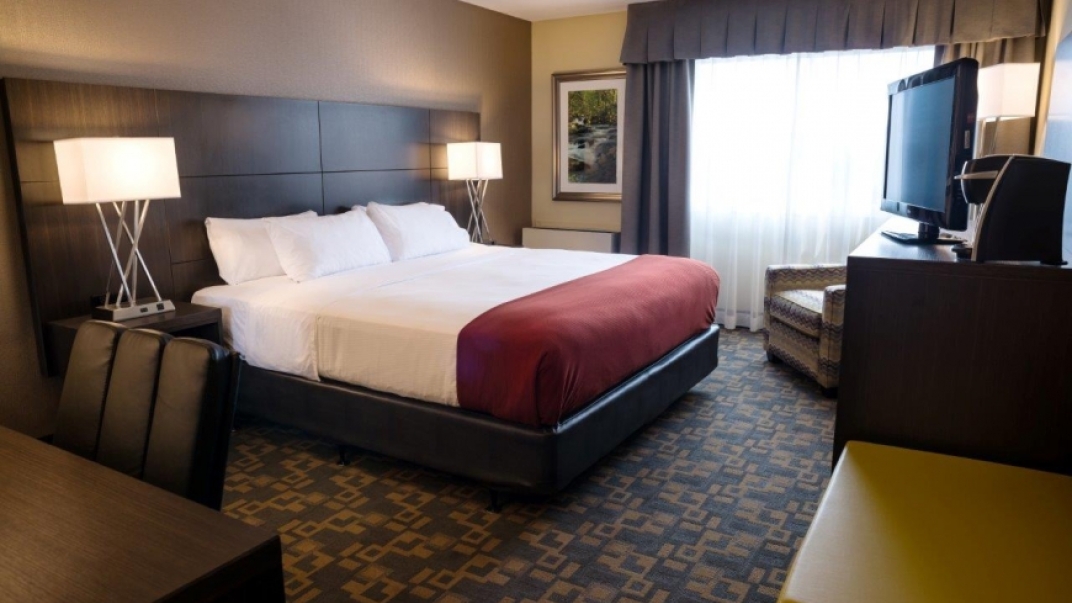 hotel room with white and red bedding with soft lighting and carpet