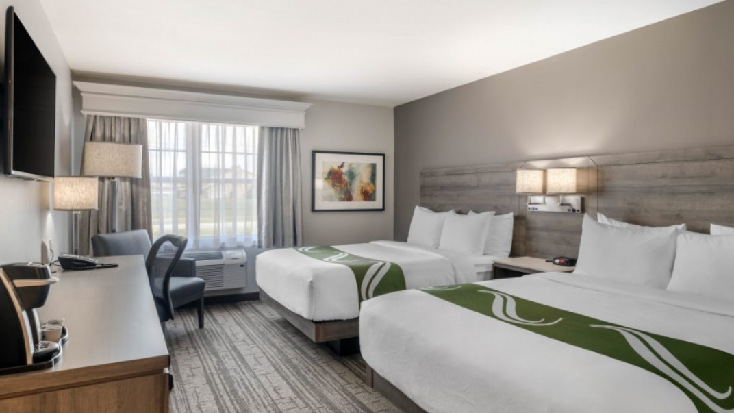 hotel room with white bedding, grey walls and a wall mounted TV