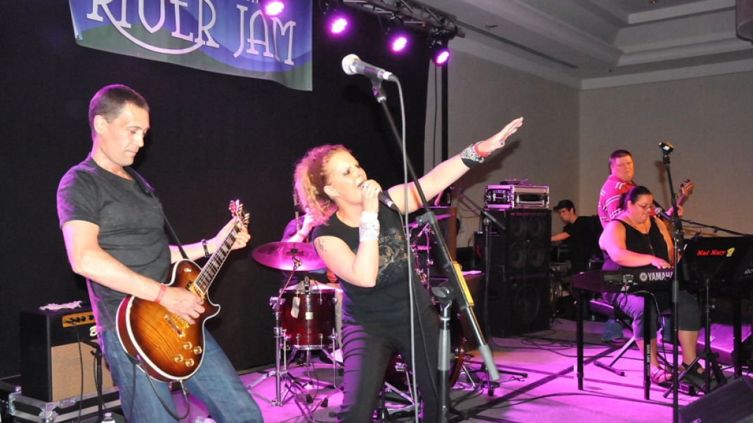 Five people singing and playing instruments on stage