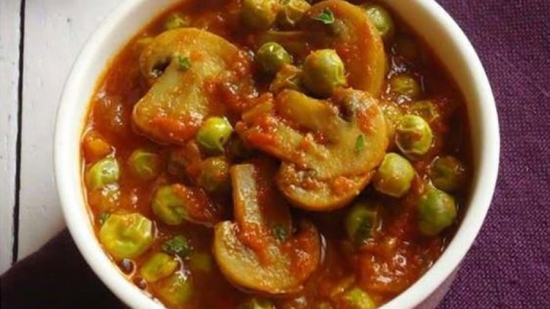 a curry dish with peas and mushrooms in a tomato base