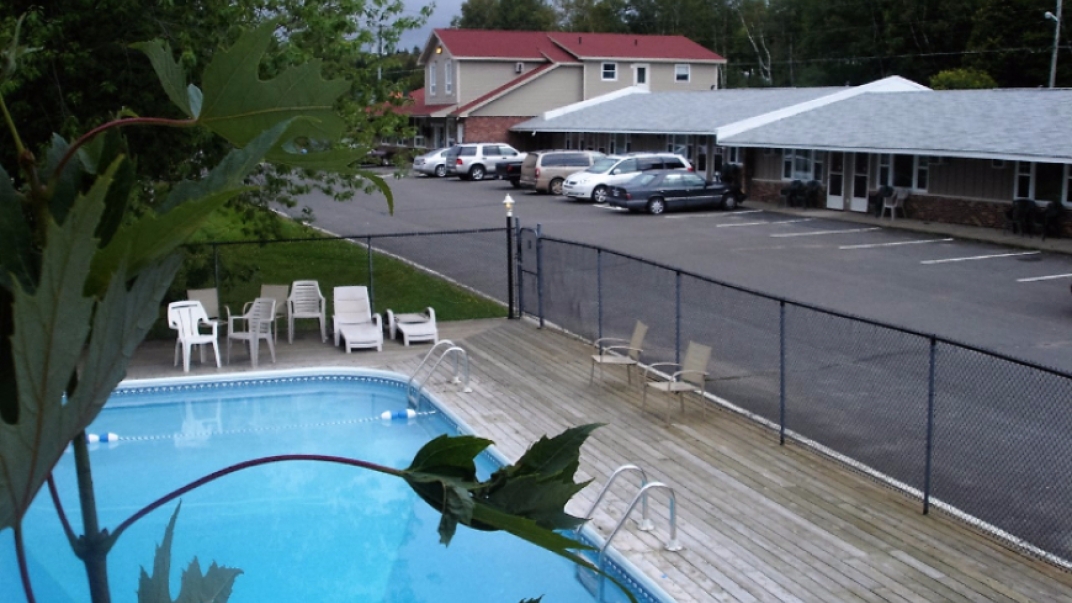 an fenced in outdoor pool and a hotel parking lot