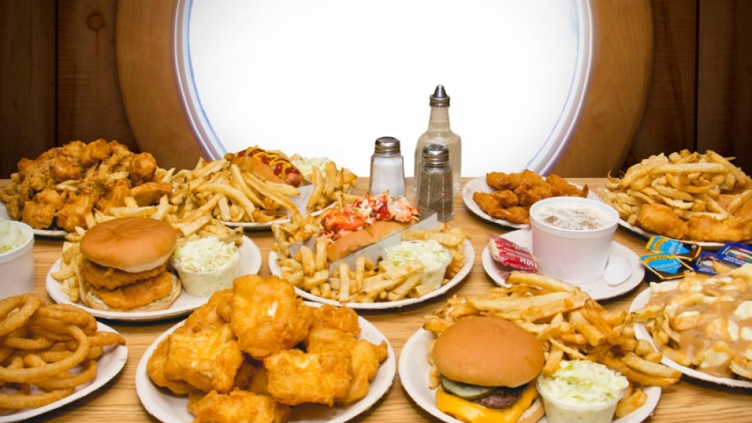 Table full of plates of food including burgers, fries, fish and chips