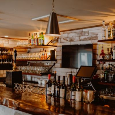 a bar with a wooden counter top and bottles on top