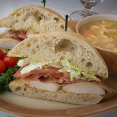 a club sandwich with soup on a pink and beige plate
