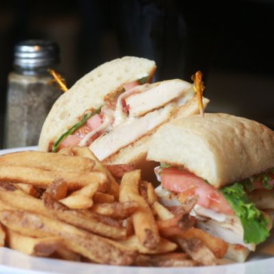 a white plate with a deli sandwich and fries