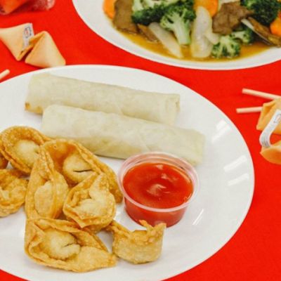 wantons and spring rolls with dip on a white plate and a red table cloth