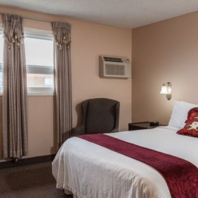 hotel room with a queen bed, white bedding and red throw pillow