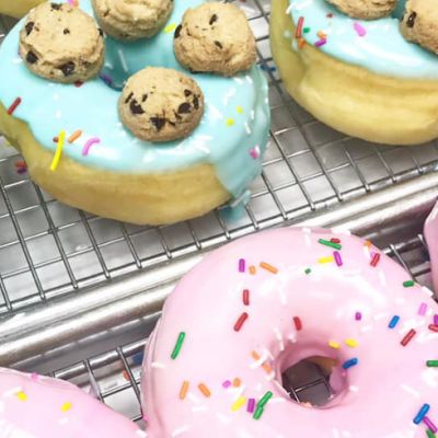 donuts with pink icing and sprinkles and blue icing topped with cookies