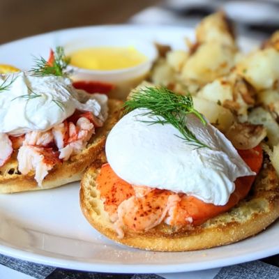 lobster Eggs Benedict with home fries on a white plate