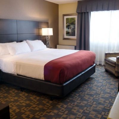 hotel room with white and red bedding with soft lighting and carpet