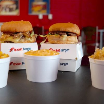 two cheese burgers with three sides in white styrofoam cups