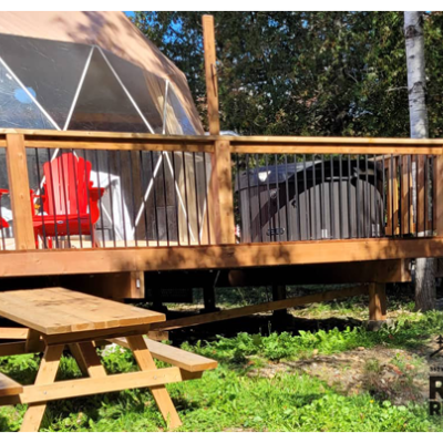 glamping tent with a deck and two bright red chairs