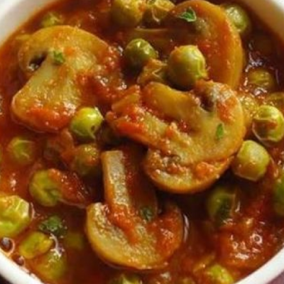 a curry dish with peas and mushrooms in a tomato base