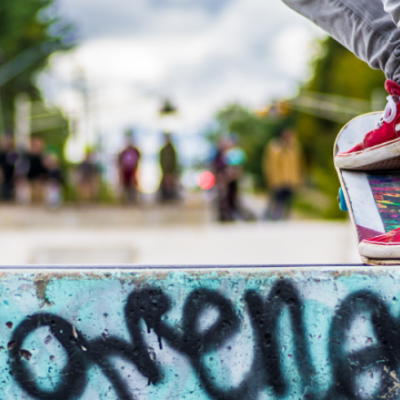 close up shot of a person wearing bright red vans on a skateboard about to drop into the skate bowl