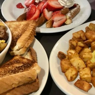 Eggs, toast, hashbrowns, strawberries and other breakfast foods on plates on a table
