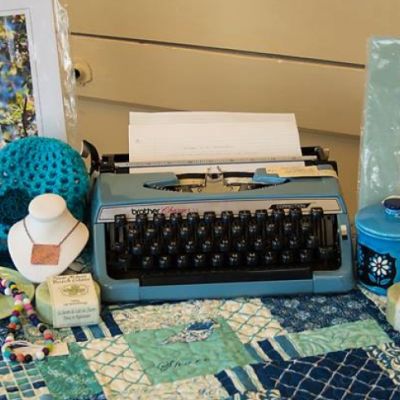 Table-spread with typewriter, handcrafted jewelry and paintings