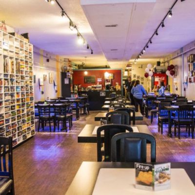Interior of board game cafe. There a chairs and tables throughout the room and shelving with board games in it