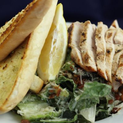plate of chicken caesar salade and garlic bread