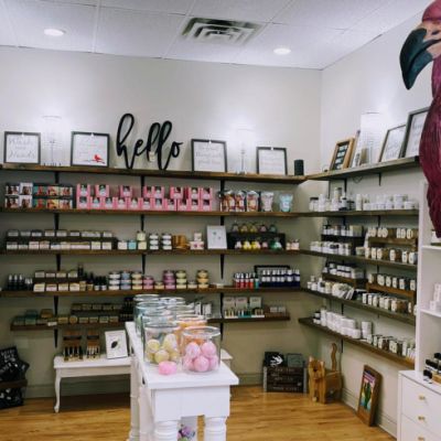 picture of Whimsy store with a right pink flamingo statue in the foreground with its wings stretched and shelves full of product in the background