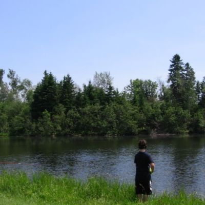 two men fishing at the edge of a river in a park