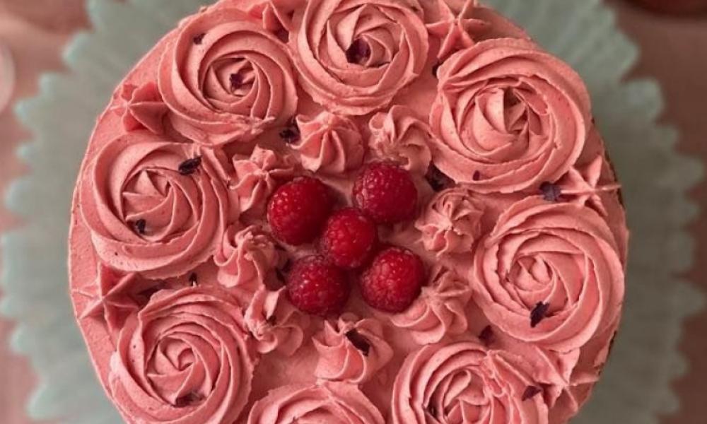 top view of a cake with pinkish red icing and raspberries on top