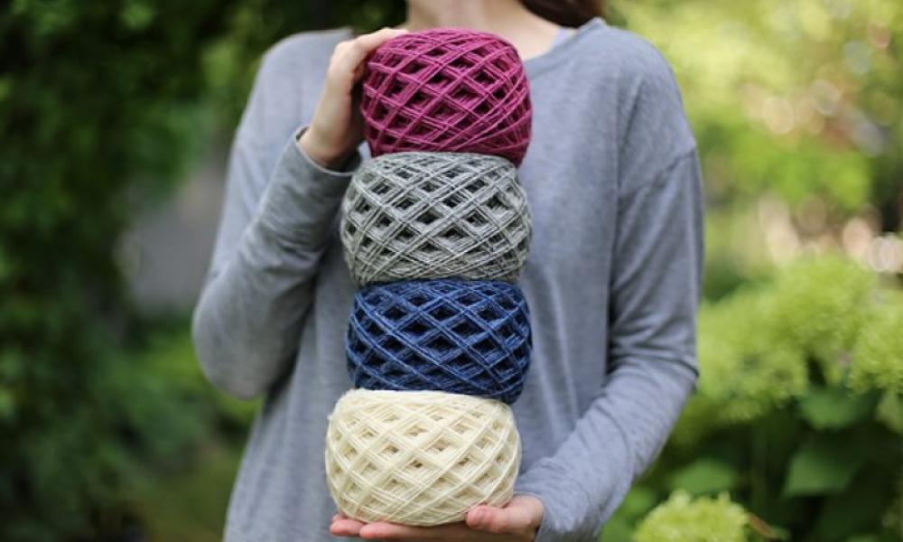Woman holding four bundles of woolen yarn