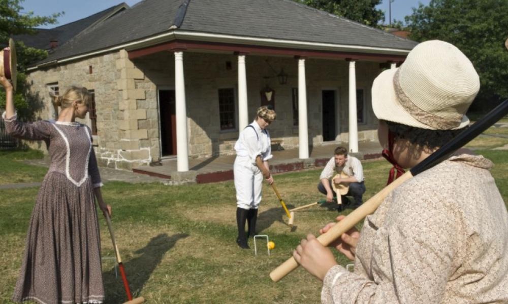 Group in historical wear plays croquet