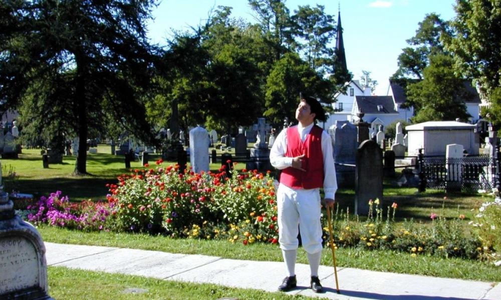 man wearing historical clothes standing in a public burial ground