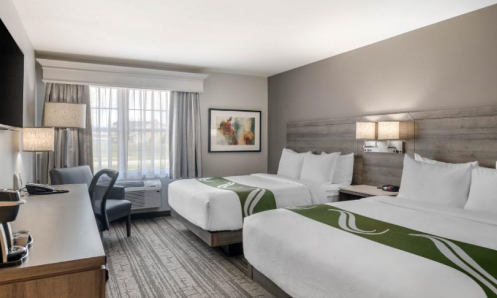hotel room with white bedding, grey walls and a wall mounted TV