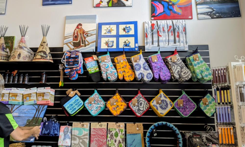 wall of wares including art, colourful patterned oven mitts and tea towels
