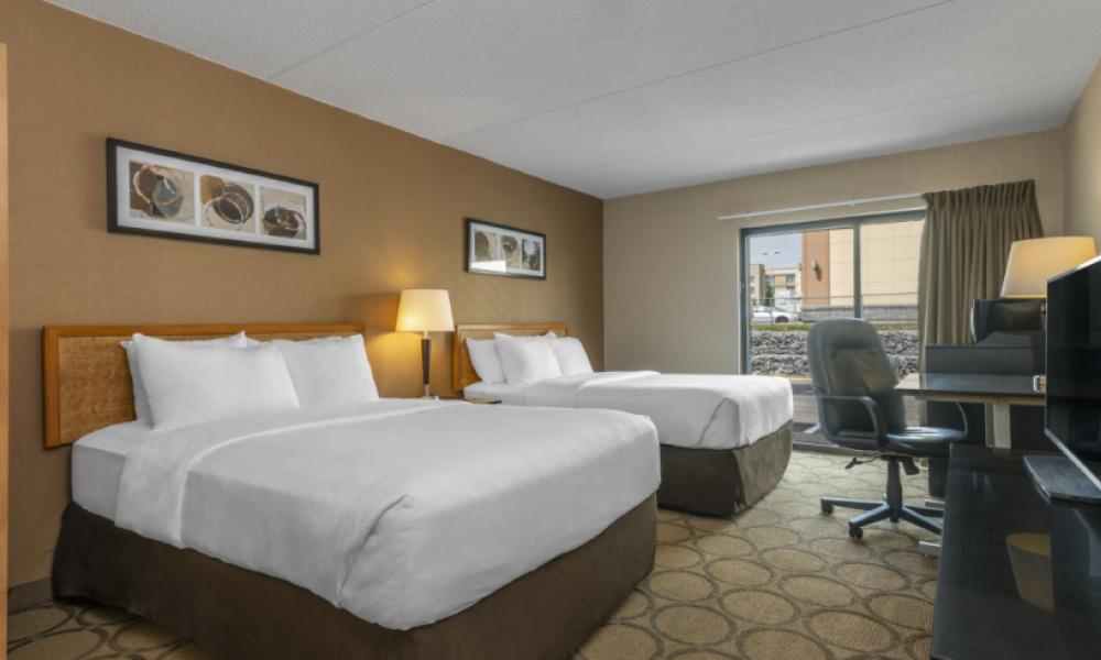 Interior shot of a hotel room with two queen beds with white blankets and pillows